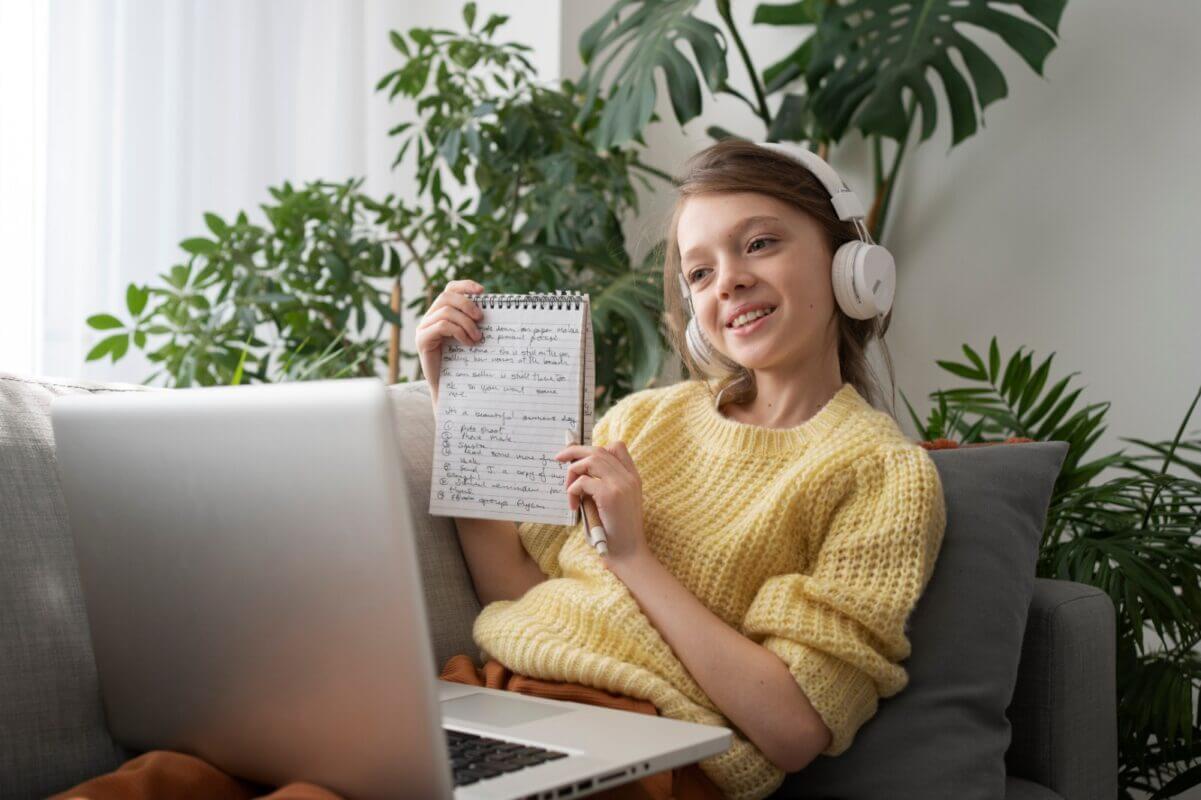 Girl learns German online with laptop, headphones, and notebook. Beginner's guide to German learning.